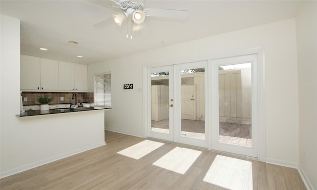 kitchen with white cabinetry, tasteful backsplash, french doors, and light wood-type flooring