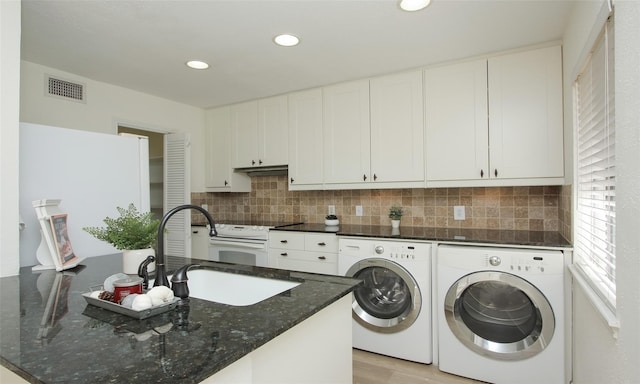 clothes washing area with sink, washer and clothes dryer, and light wood-type flooring