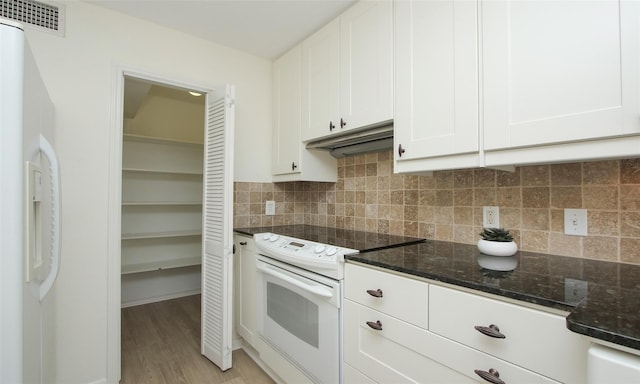 kitchen with electric stove, decorative backsplash, dark stone counters, and white cabinets