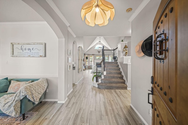 entryway featuring arched walkways, crown molding, stairway, and wood finished floors