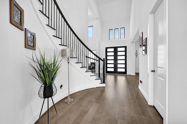 foyer entrance featuring a towering ceiling, hardwood / wood-style floors, and french doors