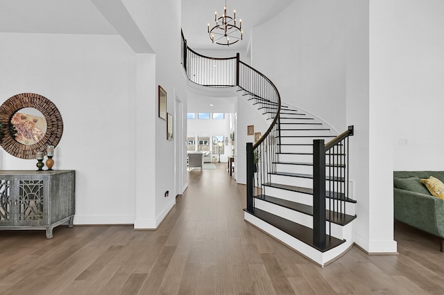 foyer featuring an inviting chandelier, hardwood / wood-style flooring, and a towering ceiling