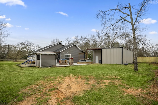 back of property featuring an outbuilding, a yard, a playground, and a deck