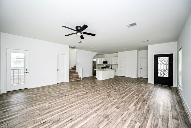 1415 E 35th St, Houston, TX 77022 - unfurnished living room featuring wood finished floors, stairs, healthy amount of natural light, and ceiling fan