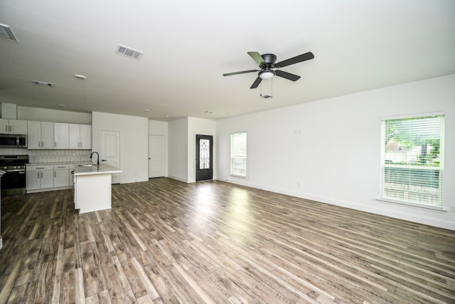 1415 E 35th St, Houston, TX 77022 - unfurnished living room featuring dark wood-type flooring, healthy amount of natural light, and ceiling fan