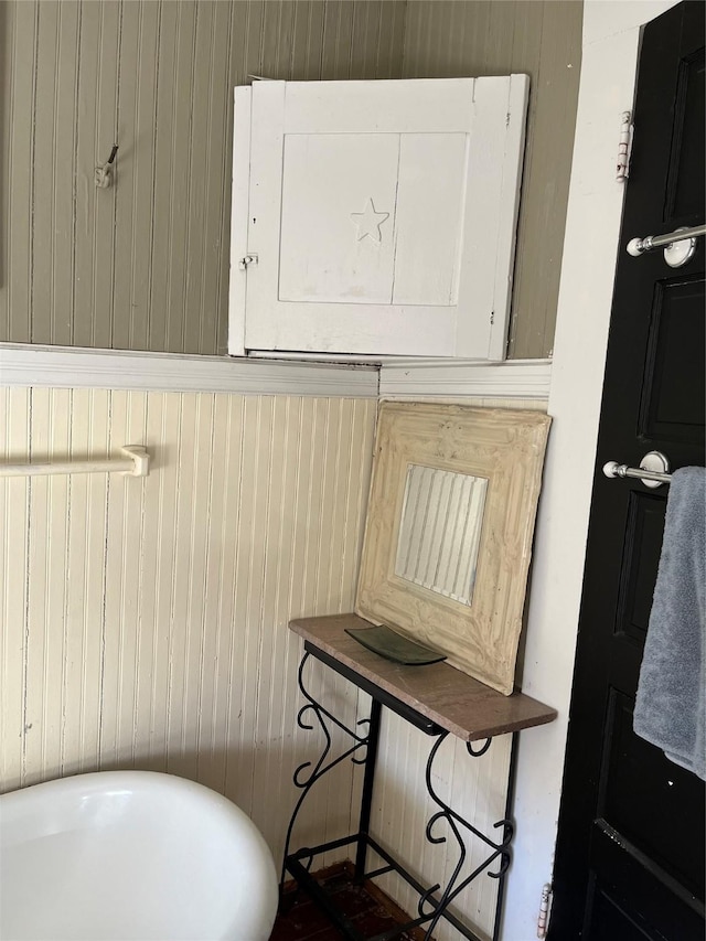 bathroom featuring a bath, electric panel, and wood walls