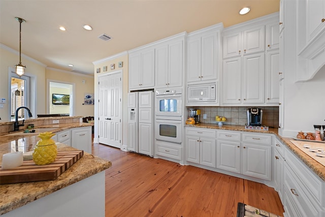 kitchen featuring white cabinets, built in appliances, sink, and decorative light fixtures