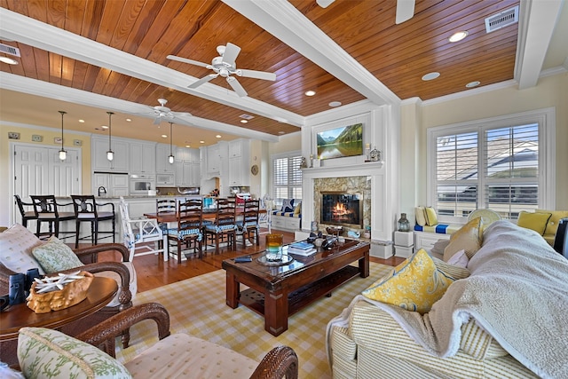 living room with light hardwood / wood-style floors, ceiling fan, wooden ceiling, ornamental molding, and beam ceiling