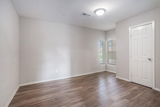 unfurnished room featuring a textured ceiling and dark hardwood / wood-style flooring