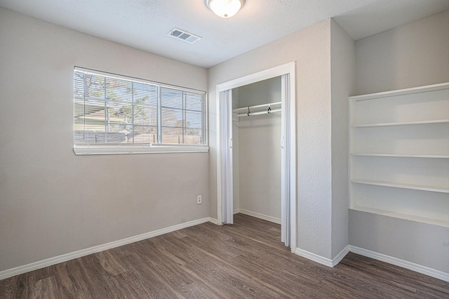 unfurnished bedroom featuring dark hardwood / wood-style floors and a closet