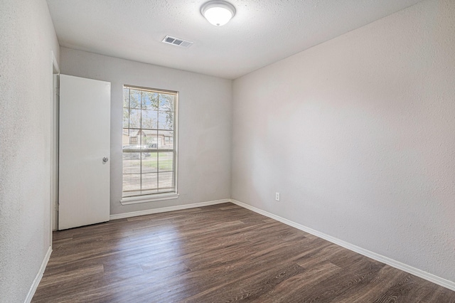 spare room featuring dark hardwood / wood-style flooring and a textured ceiling