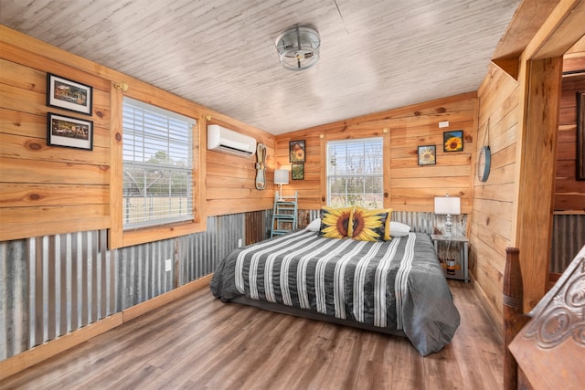 bedroom with hardwood / wood-style flooring, multiple windows, vaulted ceiling, and a wall unit AC