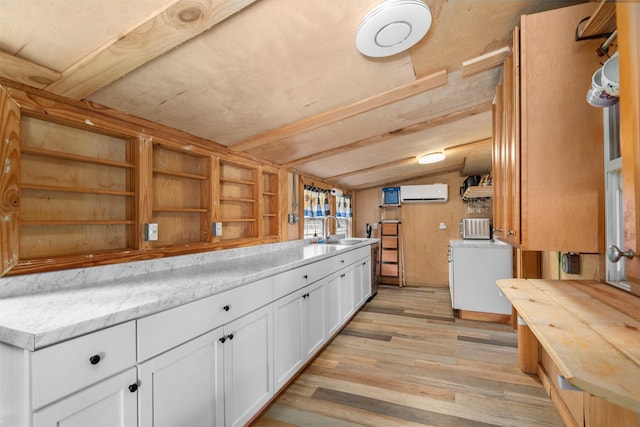 kitchen featuring sink, vaulted ceiling with beams, white cabinetry, light wood-type flooring, and a wall unit AC