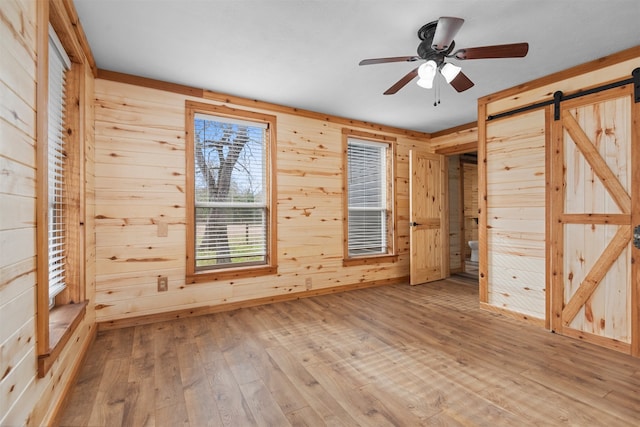 unfurnished bedroom with wood-type flooring, a barn door, and wooden walls