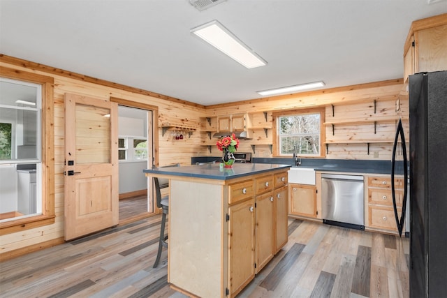 kitchen with sink, dishwasher, a kitchen breakfast bar, a center island, and black fridge