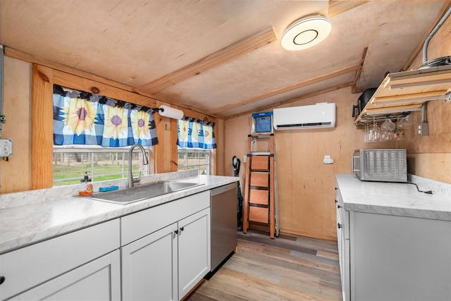 kitchen with sink, light hardwood / wood-style floors, white cabinets, stainless steel dishwasher, and an AC wall unit