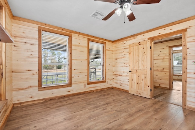 unfurnished room with wood-type flooring, ceiling fan, and wood walls