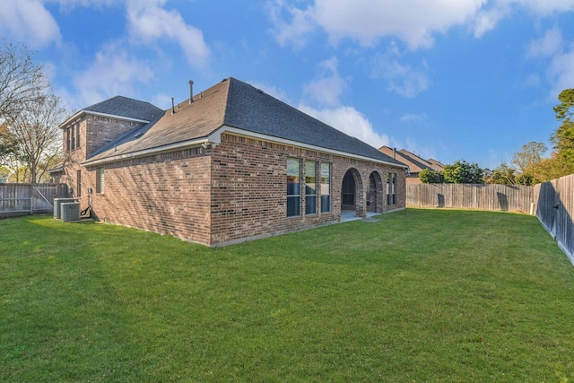 rear view of house featuring cooling unit and a yard