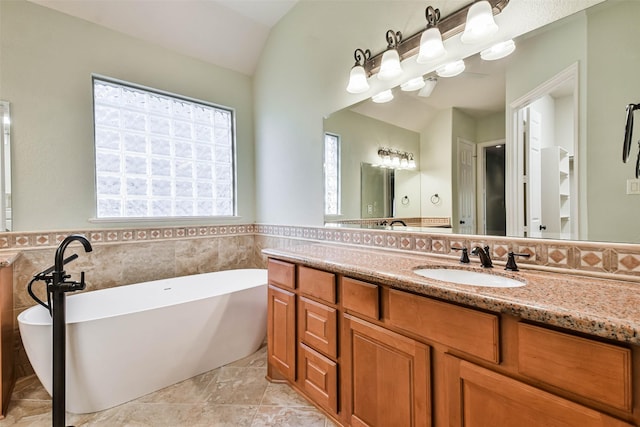 bathroom featuring vanity, vaulted ceiling, a bath, and tile walls