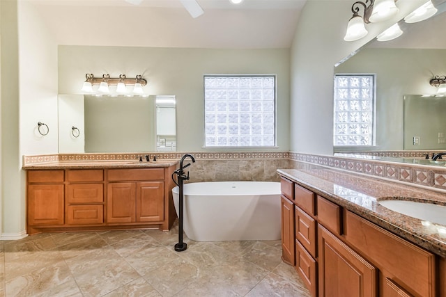 bathroom featuring lofted ceiling, vanity, and a bath