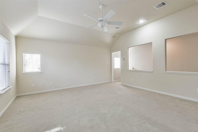 carpeted spare room with vaulted ceiling, a wealth of natural light, and ceiling fan