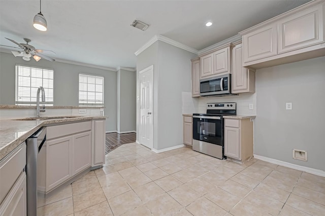 kitchen featuring pendant lighting, sink, crown molding, stainless steel appliances, and light tile patterned flooring