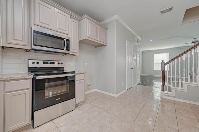 kitchen featuring stainless steel appliances, light stone countertops, decorative backsplash, and light tile patterned floors