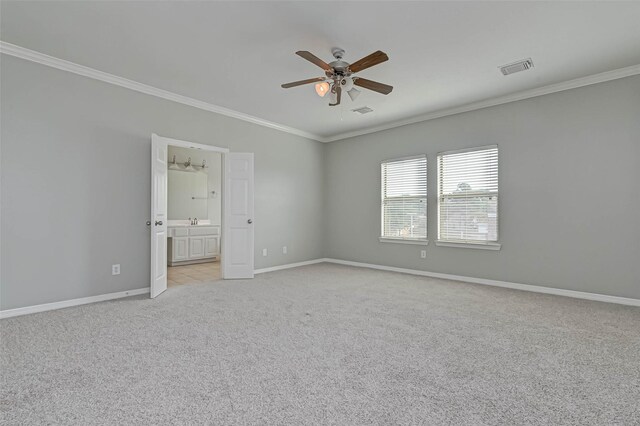 unfurnished bedroom featuring crown molding, sink, light colored carpet, and ensuite bath