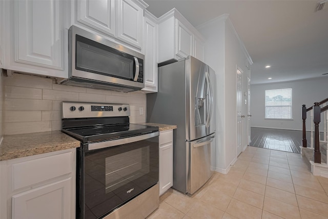7816 Stoneyway Dr, Houston, TX 77040 - kitchen featuring appliances with stainless steel finishes, light tile patterned floors, backsplash, white cabinets, and recessed lighting