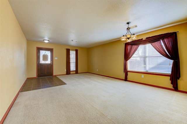 carpeted entryway featuring an inviting chandelier and a textured ceiling