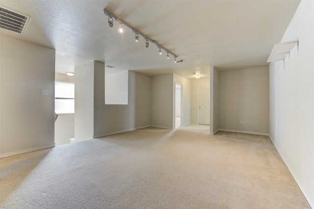 unfurnished room featuring light colored carpet, track lighting, and a textured ceiling