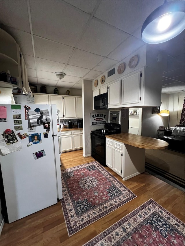 kitchen with white cabinetry, wooden counters, and black appliances