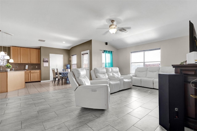 living room with plenty of natural light, ceiling fan, and vaulted ceiling