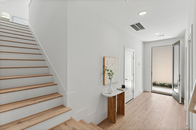 staircase with visible vents, baseboards, and wood finished floors