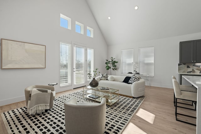 living room featuring high vaulted ceiling, light wood finished floors, and baseboards