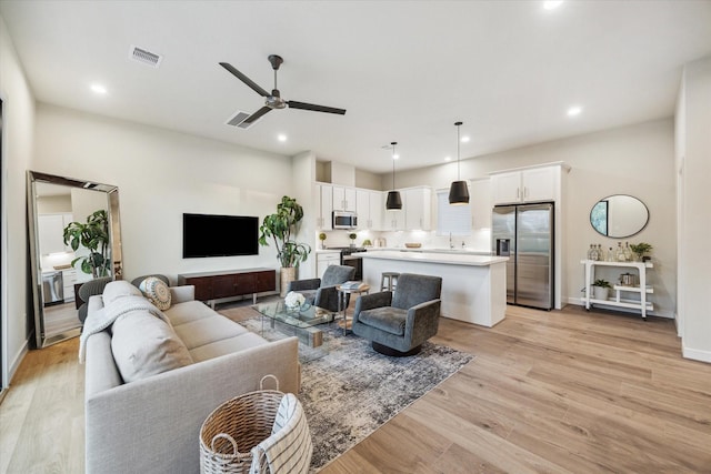 living room with ceiling fan and light hardwood / wood-style flooring