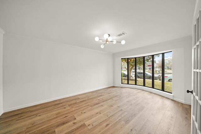 spare room featuring ornamental molding, a notable chandelier, and light wood-type flooring