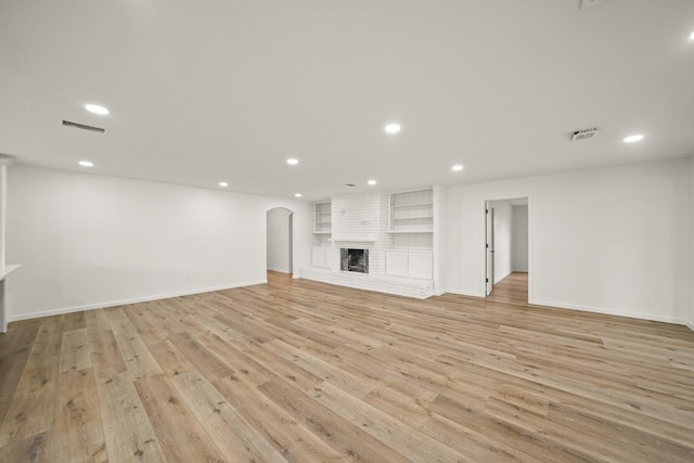 unfurnished living room with light hardwood / wood-style flooring, built in shelves, and a fireplace