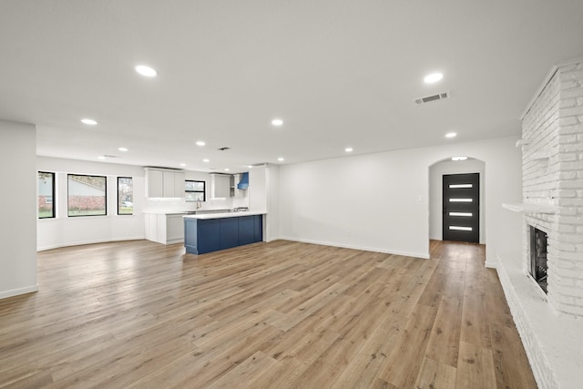 unfurnished living room with a brick fireplace and light hardwood / wood-style flooring