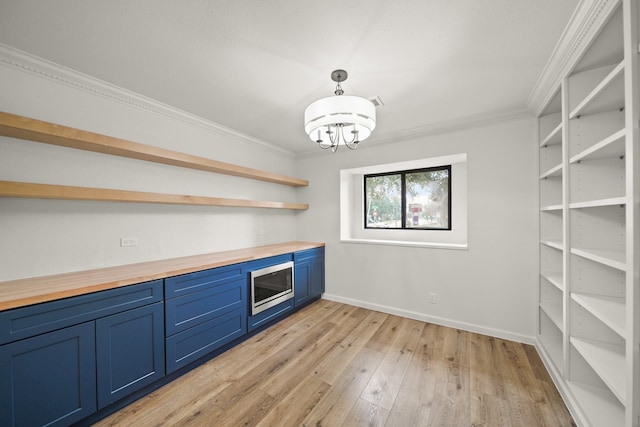 bar with butcher block countertops, crown molding, blue cabinets, decorative light fixtures, and light wood-type flooring