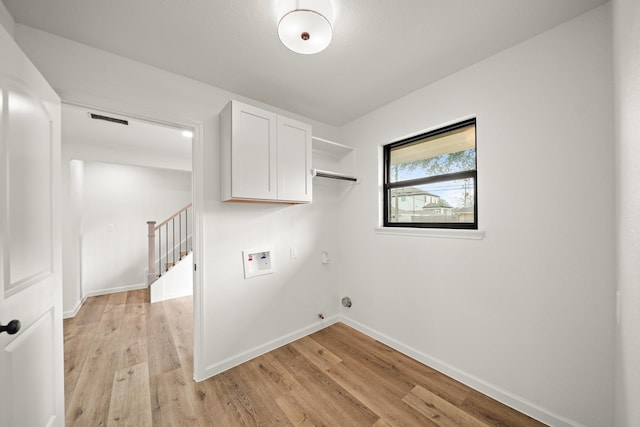 clothes washing area featuring cabinets, light hardwood / wood-style flooring, washer hookup, and hookup for a gas dryer