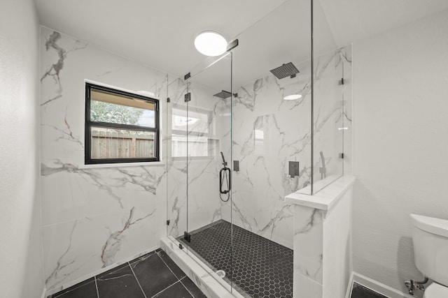 bathroom featuring a shower with door and toilet