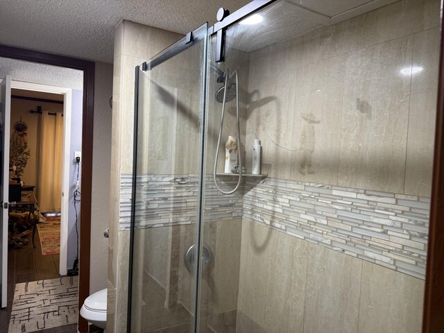 bathroom with hardwood / wood-style flooring, a shower with shower door, a textured ceiling, and toilet