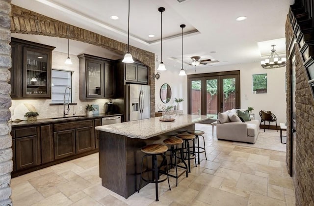 kitchen featuring a sink, dark brown cabinetry, stainless steel appliances, and stone tile floors