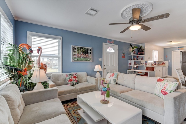 living room with crown molding, a wealth of natural light, and ceiling fan