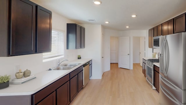 kitchen featuring light wood finished floors, appliances with stainless steel finishes, light countertops, dark brown cabinets, and a sink