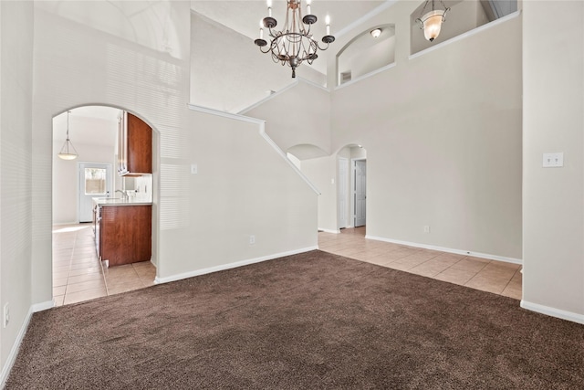 unfurnished living room with a towering ceiling, light carpet, and a notable chandelier