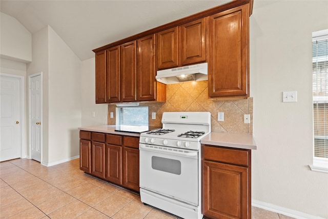 kitchen featuring lofted ceiling, backsplash, white gas range oven, and light tile patterned flooring