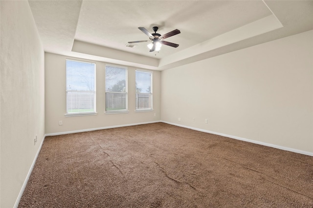 unfurnished room with carpet, ceiling fan, and a tray ceiling