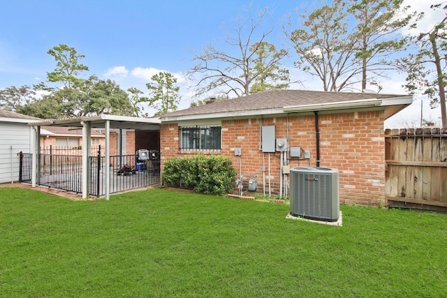 rear view of house featuring central AC, brick siding, a lawn, and fence